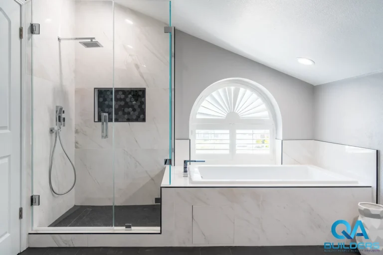 Primary bathroom with walk-in shower and tiled tub under arched window in San Jose