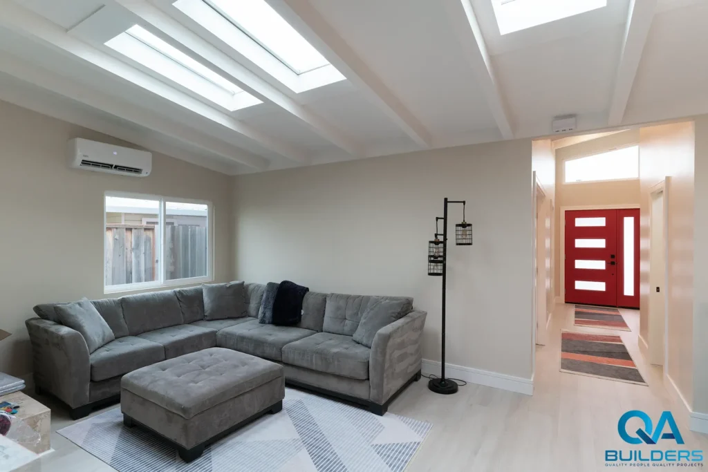 Living room with skylights in a beamed ceiling and a view to the red front door, San Mateo