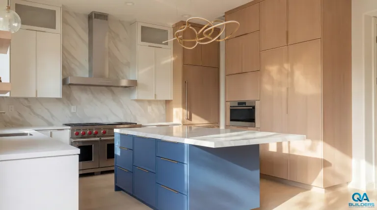 Blue kitchen island with a marble-look top facing the range wall and light wood pantry cabinets, San Jose
