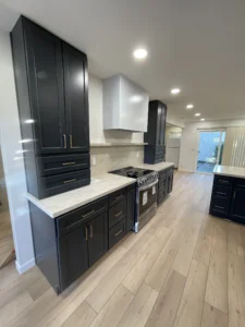 Dark shaker cabinets with brass pulls, white range hood and stone-look backsplash in San Jose