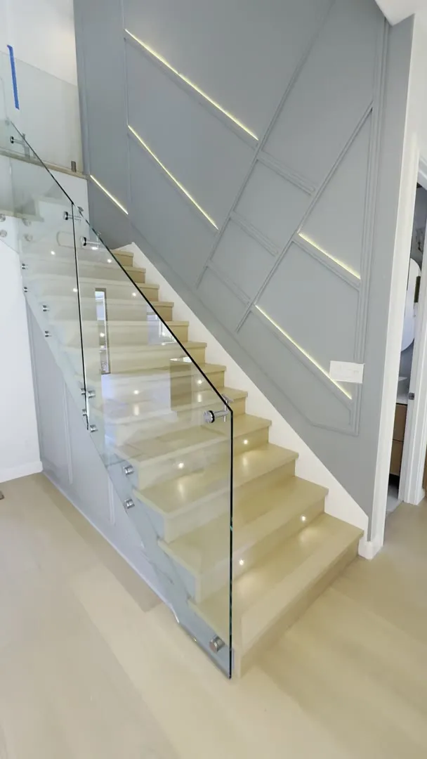 Lit oak staircase with a glass railing in San Jose